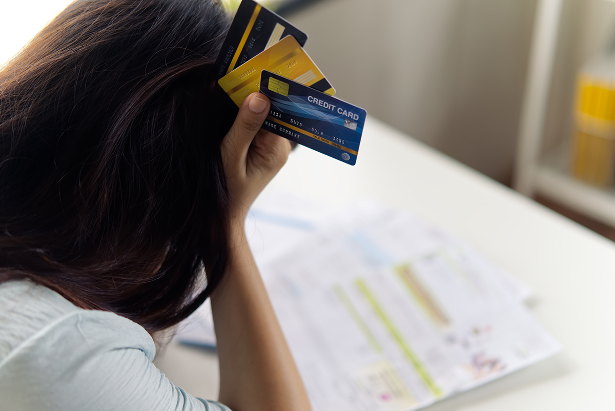 Woman in debt holding credit cards, looking at a financial document.