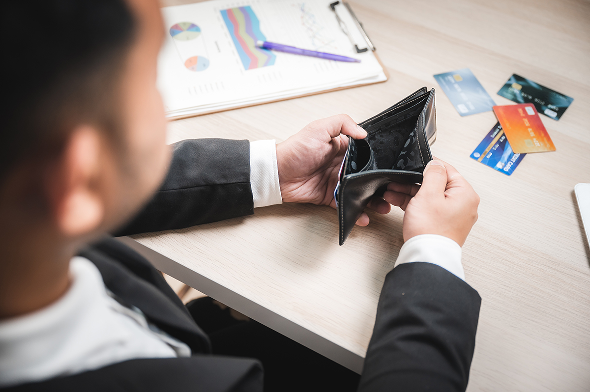 Businessman opening empty wallet, credit cards maxed out.